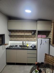 eine kleine Küche mit Spüle und Kühlschrank in der Unterkunft Novo lar Garopaba Terraço in Garopaba