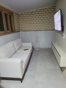 ein Wohnzimmer mit einem weißen Sofa und einem Fernseher in der Unterkunft Novo lar Garopaba Terraço in Garopaba