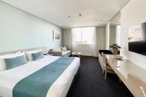 Cette chambre comprend un grand lit et une télévision. dans l'établissement Coogee Sands Hotel & Apartments, à Sydney