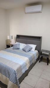 a bedroom with a bed with blue pillows and a lamp at Casa equipada Cd Valles in Ciudad Valles