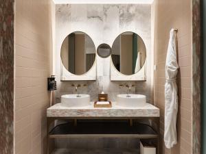 a bathroom with two sinks and two mirrors at The Porter House Hotel Sydney - MGallery in Sydney