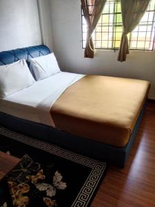 a bed sitting in a room with two windows at khairul homestay taman tengiri seberang jaya in Kampong Telok