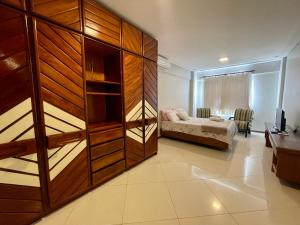 1 dormitorio con 1 cama y una gran pared de madera en 3 SUITES Vista Mar - WI-FI, PISCINA, SAUNA, ACADEMIA, GARAGEM 2 CARROS en Ilhéus
