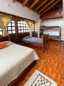 sypialnia z 2 łóżkami i drewnianą podłogą w obiekcie Chez Alicia Hostal w mieście Villa de Leyva