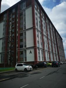 un gran edificio rojo y blanco con coches aparcados delante en Putatan Platinum Apartment with Pool, en Kota Kinabalu