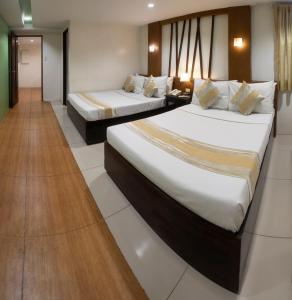 um quarto de hotel com duas camas e um corredor em ACL Suites em Manilla