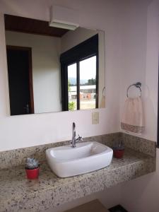 a white sink in a bathroom with a mirror at Pousada Divino Oleiro - Gov. Celso Ramos in Governador Celso Ramos