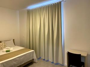 um quarto com uma cama e uma janela com cortinas em Pousada Divino Oleiro - Gov. Celso Ramos em Governador Celso Ramos