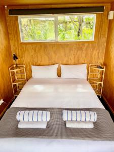 Cama en habitación pequeña con ventana en Athenree Hot Springs & Holiday Park, en Waihi Beach