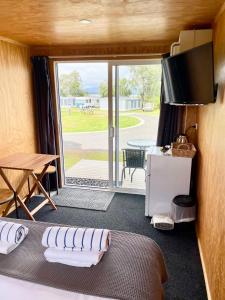 Habitación con cama y puerta corredera de cristal en Athenree Hot Springs & Holiday Park en Waihi Beach