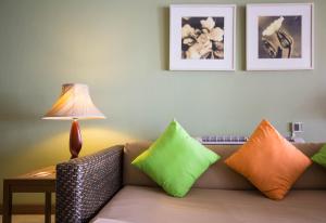 バーン・クロンムアンにあるセンタラ チャーン タレー リゾート アンド ヴィラ トラットのカラフルな枕とランプ付きのソファ