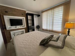 1 dormitorio con 1 cama y TV en la pared en Elegante Casa de 4 Habitaciones a Solo 15 Minutos del Corazón de la Ciudad, en San José