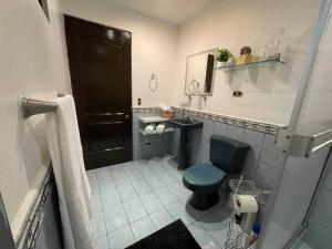 baño con aseo verde y lavamanos en Elegante Casa de 4 Habitaciones a Solo 15 Minutos del Corazón de la Ciudad en San José