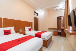 a hotel room with two beds and a flat screen tv at RedDoorz Syariah near RS Mata Padang in Padang