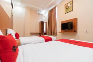 a hotel room with two beds and a flat screen tv at RedDoorz Syariah near RS Mata Padang in Padang