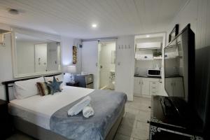 a bedroom with a large bed and a kitchen at Hideaway Noosa Men Only Beach Resort in Peregian Beach