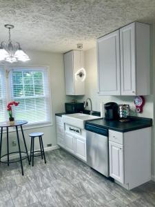 cocina con armarios blancos, fregadero y mesa en Trestle Creek Farm- farmhouse suite, en Bloomington