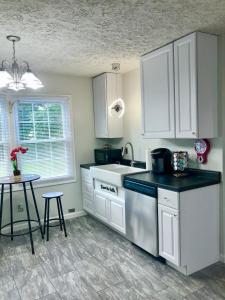 a kitchen with white cabinets and a sink and a table at Trestle Creek Farm- farmhouse suite in Bloomington