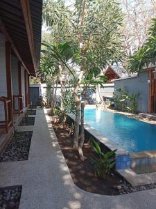 a swimming pool next to a house with trees at Villa PhyPhy in Gili Trawangan
