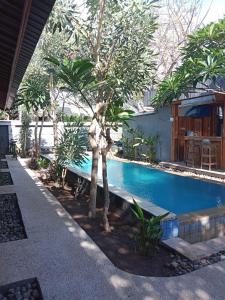 a swimming pool in front of a house with trees at Villa PhyPhy in Gili Trawangan