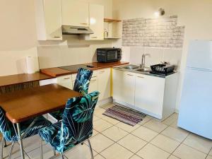 a kitchen with a table and a sink and a refrigerator at Studio Papeete Lodge - Kaoha Nui in Papeete +3 photos