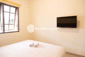 a bedroom with a bed with a flatscreen tv on the wall at House Of Cokro near Malioboro Area Mitra RedDoorz in Ngabean