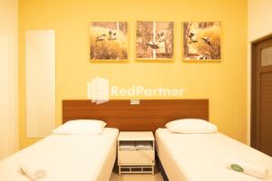 two beds in a room with a red partner sign on the wall at House Of Cokro near Malioboro Area Mitra RedDoorz in Ngabean