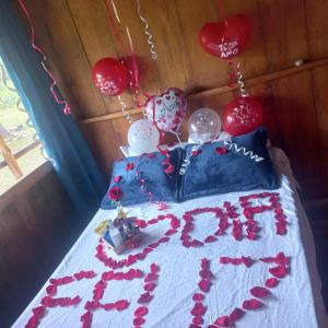 a birthday cake with hearts and balloons on a bed at glamping volvere san GabrieL 