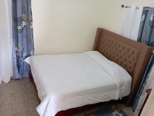 1 cama con sábanas blancas y cortinas azules en una habitación en Lugar encantador en el Malecón Paraíso, Barahona., en Paraíso