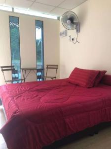 a large red bed in a room with windows at Laman Cottage @ Brisu, Melaka in Melaka