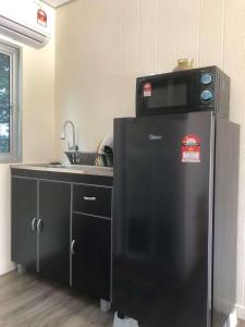 a kitchen with a microwave on top of a refrigerator at Laman Cottage @ Brisu, Melaka in Malacca