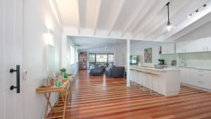 a kitchen and living room with white cabinets and wood floors at Hamilton House in Yamba