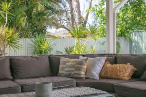 a brown couch with pillows on a patio at Hamilton House in Yamba