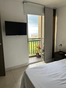1 dormitorio con cama y vistas a un balcón en APARTAMENTO CONDINA PEREIRA, en Pereira