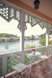 een balkon met een tafel en stoelen en uitzicht op een rivier bij Hotel Paradise Road in Koetaisi