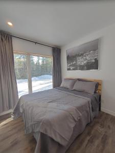 a bedroom with a large bed and a large window at Les Chalets Double K # 1 in Saint-Alexis-des-Monts