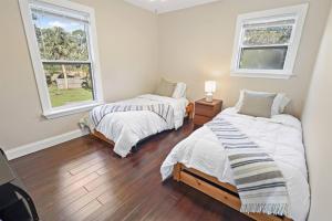 two beds in a room with two windows at Casa Arena Relaxing Beach House w/ Patio in Vero Beach