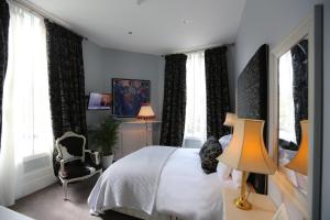 a bedroom with a bed and a chair and windows at The Crown and Sceptre in London