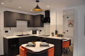 een keuken met zwart-witte kasten en oranje stoelen bij Luxury Studio- MK central- 5 MINS DRIVE TO TRAIN STATION-DIRECT TRAINS TO LONDON, BIRMINGHAM in Milton Keynes