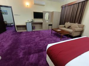 a hotel room with a bed and a couch and a tv at ROYAL HOTEL in Muscat