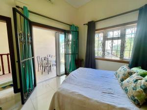 1 dormitorio con 1 cama con cortinas verdes y mesa en Calypso - Maison face au lagon - Trou aux Biches, en Trou aux Biches