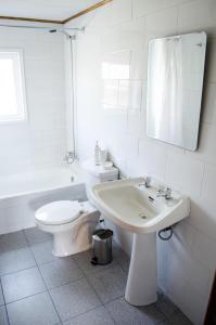 Baño blanco con aseo y lavamanos en Casa Pehuen, Cabañas, en Villarrica