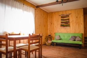 sala de estar con sofá verde y mesa en Casa Pehuen, Cabañas, en Villarrica
