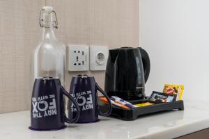 eine Theke mit zwei Kaffeetassen und einer Flasche darauf in der Unterkunft FOX Lite Hotel Samarinda in Samarinda