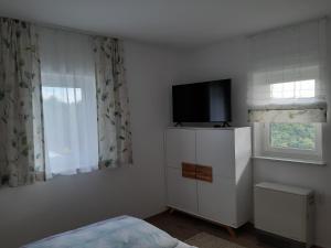 Ferienhaus Urschitz في Eichberg Arnfels: غرفة نوم مع تلفزيون في أعلى خزانة بيضاء