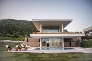 a house with a swimming pool in front of it at VARKO LUXURY SUITES in Paleros