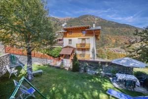 a house with a yard with chairs and a building at Casa Penasa appartamento 2 in Commezzadura