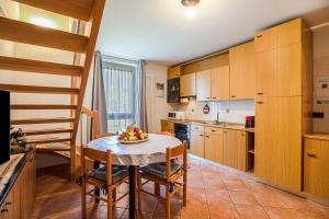uma cozinha com armários de madeira e uma mesa e cadeiras em Casa Penasa Appartamento 1 em Commezzadura