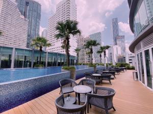 uma piscina com mesas, cadeiras e edifícios em Vortex Suites KLCC By Welt em Kuala Lumpur