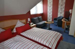 a bedroom with a bed and a couch and a chair at Pension Ederstrand in Frankenberg